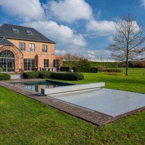 Couverture Coverseal grise déployée sur la piscine d'une maison en brique