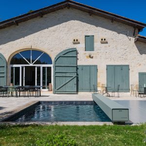 Couverture Coverseal sur la piscine d'une maison en pierre aux volets verts