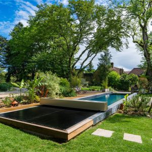 Couverture Coverseal noire fermée sur une piscine dans un jardin arboré